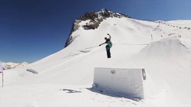 SOCHI, RÚSSIA - 1 de abril de 2016: Snowboarder jump from springboard, grab board by hand. Montanhas nevadas. Céu azul. Paisagem — Vídeo de Stock