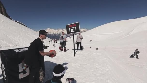 Sotschi, Russland - 1. April 2016: Mann wirft Ball zu Snowboarder machen Sprung auf Sprungbrett. Basketball. Kameramann. — Stockvideo