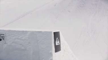 Sochi, Rusya Federasyonu - 1 Nisan 2016: Sıçrama tahtası kayakçı atlamak ayakları havada şişiriyor. Karlı dağlar. Güneşli bir gün. Mavi gökyüzü. Aşırı