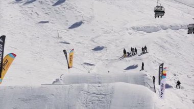 Sochi, Rusya Federasyonu - 1 Nisan 2016: yüksek atlama sıçrama tahtası üzerinden yapmak Snowboarder havada ters çevirin. Karlı dağlar. Güneşli bir gün. İnsanlar