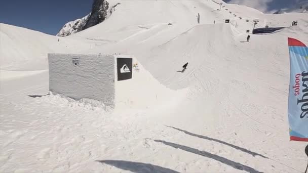 SOCHI, RÚSSIA - 1 de abril de 2016: Snowboarder salto em altura do trampolim. Faz lançamentos extremos. Cameraman. Ensolarado — Vídeo de Stock