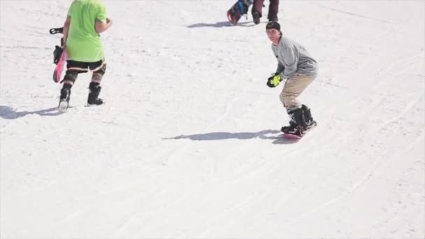 Sotschi, Russland - 1. April 2016: Snowboarder fahren auf Sprungbrett mit Schneeball in der Hand. Menschen. Skigebiet. Sonne — Stockvideo