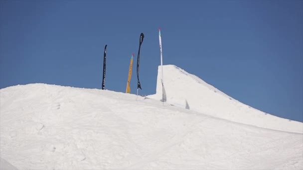 SOCHI, RUSSIA - APRIL 1, 2016: Snowboarder make high jump from springboard. Ski resort. Mountains. Blue sky. — Stock Video