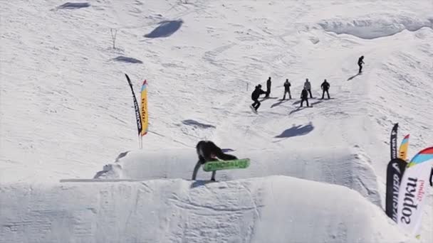 Soči, Rusko - 1. dubna 2016: Snowboardista skok z odrazový můstek, selhání. Horách sníh. Slunečný den. Lidé. Extrémní sport. — Stock video
