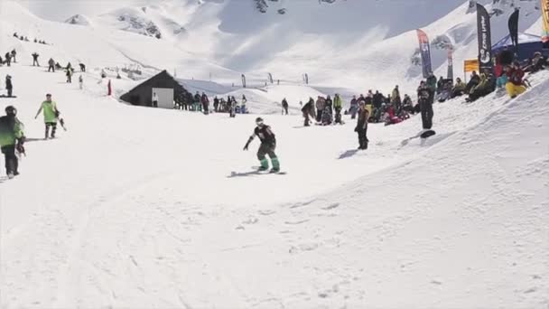 Sochi, Rusko - 1. dubna 2016: Snowboardista v cap jízda na SpringBoardu házet sněhové koule na basketbalový koš. — Stock video