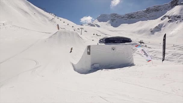 SOCHI, RUSSIE - 1er AVRIL 2016 : Le snowboardeur en combinaison jaune saute du tremplin pour faire un plein flip dans l'air. Paysage de montagnes enneigées — Video