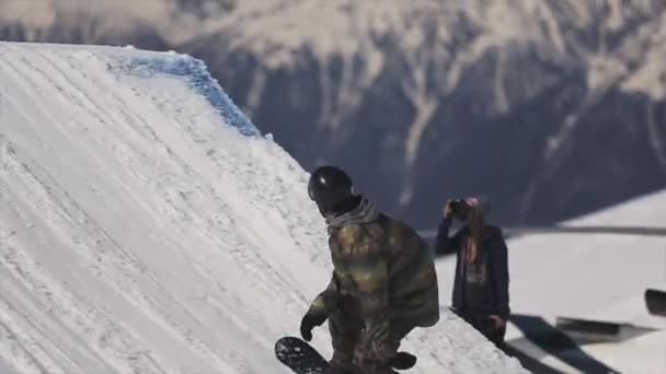 Sochi, Rusko - 1. dubna 2016: Snowboardista skok do výšky z odrazový můstek. Zkontrolujte nebezpečné Salto. Hory. — Stock video