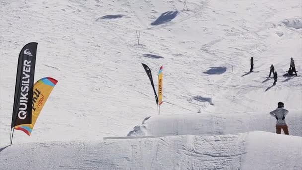 SOCHI, RUSSIA - 1 APRILE 2016: Gli snowboarder cavalcano sui trampolini. Montagne innevate. Giornata di sole. Gente. Estrema attività. Località sciistica — Video Stock