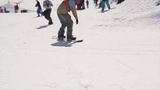 SOCHI, RÚSSIA - 1 de abril de 2016: Snowboarder jump from springboard behind basketball basket. Dia ensolarado. Pessoas — Vídeo de Stock