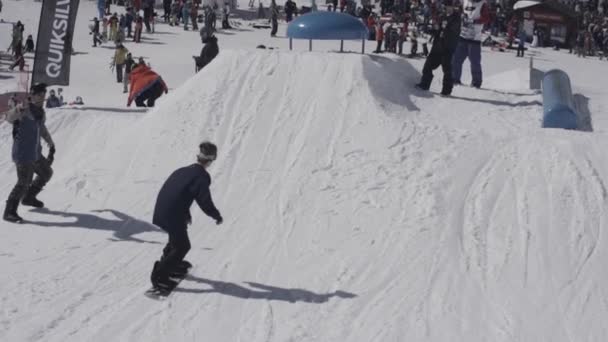 Snowboarder springen über Sprungbrett. Landschaft verschneiter Berge. Kameramann. sonniger Tag. Skilifte