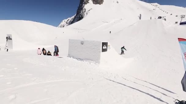 Sotschi, Russland - 1. April 2016: Snowboarder machen Hochsprung vom Sprungbrett, beugen die Füße, stürzen am Hang. sonnig — Stockvideo