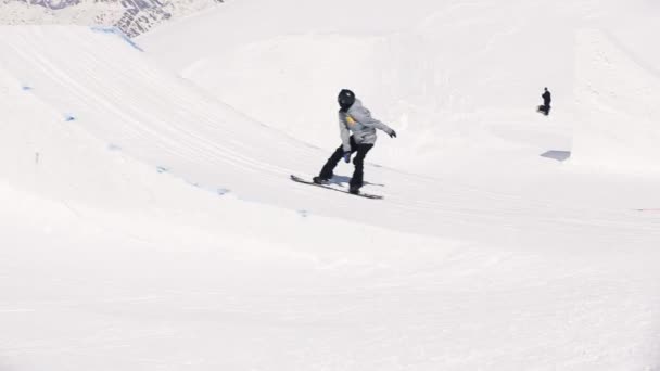 SOCHI, RUSSIE - 1er AVRIL 2016 : Le snowboardeur fait un saut en hauteur depuis le tremplin, fléchit les pieds dans l'air. Station de ski. Soleil — Video