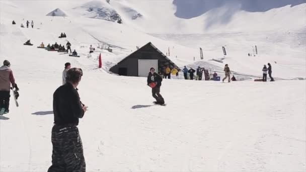 SOCHI, RÚSSIA - 1 de abril de 2016: Passeio de snowboarder no trampolim jogue bola no cesto de basquete. Sol. Audiência — Vídeo de Stock