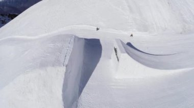 Sochi, Rusya Federasyonu - 2 Nisan 2016: ateş snowboard sıçrama sıçrama tahtası üzerinden yapmak Quadrocopter çevir. Dağlar. Güneş