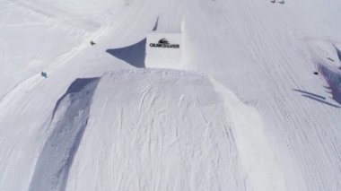 Sochi, Rusya Federasyonu - 2 Nisan 2016: Quadcopter ateş snowboard sıçrama tahtası atlama, kar üzerinde binmek. Güneşli