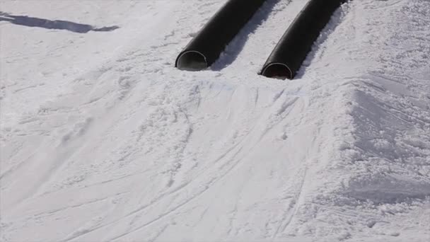 SOCHI, RUSIA - 1 DE ABRIL DE 2016: Paseo de esquiador por tuberías. Un trampolín. Estación de esquí. Montañas. Día soleado. Snowboarder — Vídeos de Stock