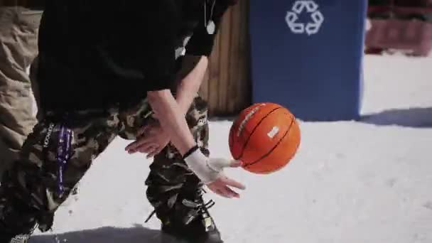 SOCHI, RUSIA - 1 DE ABRIL DE 2016: El hombre juega con la pelota de baloncesto en la nieve. Estación de esquí. Encamp. Día soleado. Gafas de sol — Vídeos de Stock