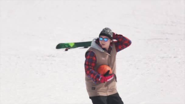 SOCHI, RUSIA - 1 DE ABRIL DE 2016: Paseo de snowboarder en la pelota de lanzamiento de trampolín en la canasta de baloncesto. Gafas de sol . — Vídeo de stock