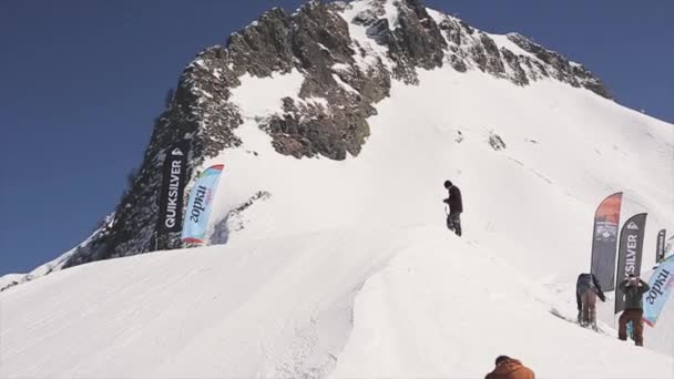 Sochi, Ryssland - April 1, 2016: Skidåkare gör flip i luften, rida på backen. Landskap med snötäckta berg. Ski resort. — Stockvideo