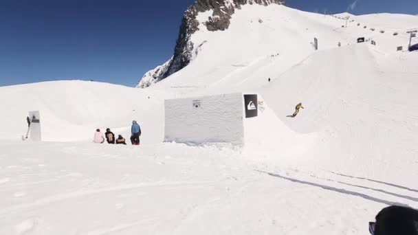 SOCHI, RÚSSIA - ABRIL 1, 2016: Snowboarder em terno amarelo fazer salto em altura do trampolim, passeio na encosta . — Vídeo de Stock