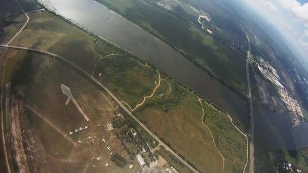 Профессиональный прыгун с парашютом, летящий над зелеными полями, рекой. Крайне. Высота — стоковое видео