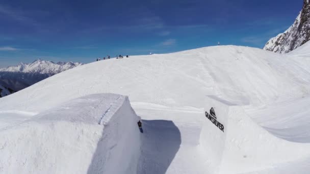 Sochi, Ryssland - April 2, 2016: Quadrocopter skjuta snowboardåkare hoppa från springboard. Bergen. Blå himmel. Soligt — Stockvideo