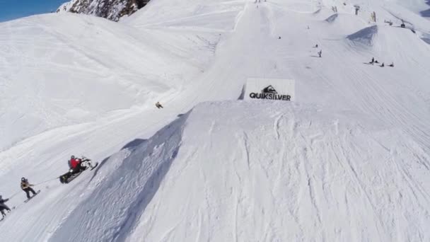 Sochi, Ryssland - April 2, 2016: Rida Quadrocopter skjuta snowboardåkare på snöskoter på sluttningen. Bergen. Soligt — Stockvideo