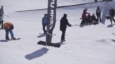 Soçi, Rusya - 2 Nisan 2016: Snowboarder slayt üzerinde demiryolu üzerinde kayak merkezi. Güneşli bir gün. Karlı dağlar. Kameraman