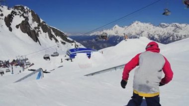 Soçi, Rusya - 2 Nisan 2016: Snowboarder slayt üzerinde demiryolu, flip. Güneşli bir gün. Kayak Merkezi. Dağlar. Aşırı spor