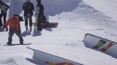 Soçi, Rusya - 2 Nisan 2016: Snowboarder slayt üzerinde demiryolu üzerinde kayak merkezi. Başarısız. Güneşli bir gün. Dağlar. İnsanlar.