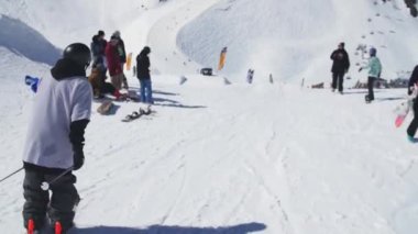 Soçi, Rusya - 2 Nisan 2016: Kayakçı slayt yamaçta, demiryolu üzerinde atlamak. Güneşli bir gün. Kayak Merkezi. Karlı dağlar.