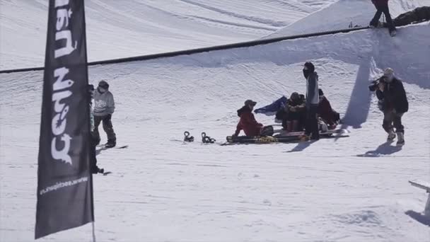 SOCHI, RUSSIE - 2 AVRIL 2016 : Le snowboardeur fait un retour en arrière sur le rail sur la station de ski. Ensoleillé. Des montagnes. Caméraman — Video