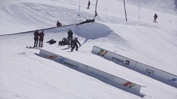 Sochi, Rusland - 2 April 2016: Snowboarder uitglijdt op rail, maken spiegelen. Skigebied. Zonnige dag. Bergen. — Stockvideo