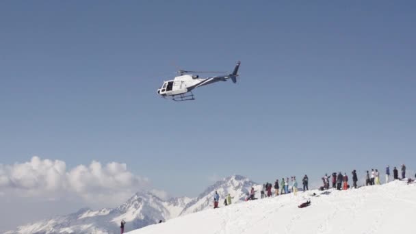 SOCHI, RÚSSIA - 2 de abril de 2016: Helicóptero voa da estação de esqui. Montanhas nevadas. Público. Dia ensolarado. Céu azul — Vídeo de Stock