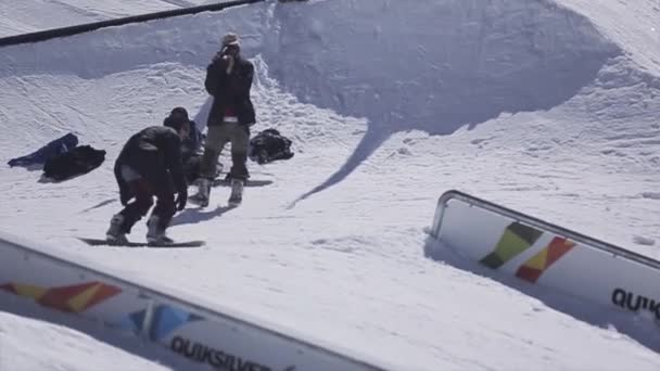 SOCHI, RUSIA - 2 DE ABRIL DE 2016: Deslizamiento de snowboarder sobre raíl, pero cayendo. Estación de esquí. Día soleado. acrobacias extremas . — Vídeo de stock