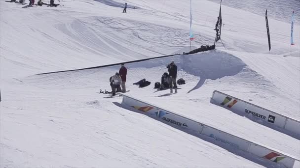 Sochi, Rusko - 2. dubna 2016: Snowboardista, aby upadnout na železnici. Lyžařské středisko. Sunny. Hory. Kameraman. — Stock video
