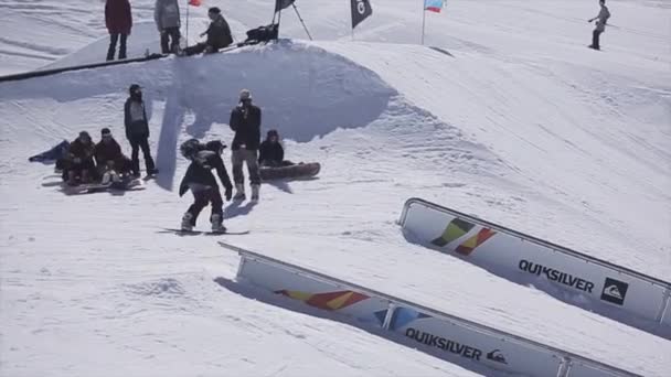 Sochi, Oroszország - április 2-án, 2016: Snowboardos csúszik a vasúti, a ski resort. Hogy a mutatvány. Süt a nap. Havas hegyek — Stock videók