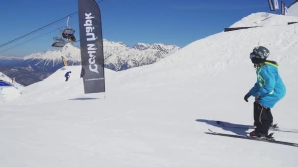 SOCHI, RUSIA - 2 DE ABRIL DE 2016: Deslizamiento del esquiador en la pendiente, saltar en el carril, hacer voltear. Soleado. Estación de esquí. Montaña nevada — Vídeos de Stock