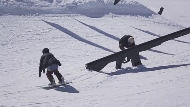 Sochi, Rusland - 2 April 2016: Snowboarder dia op rail, make hoogspringen. Skigebied. Zonnige dag. Actieve sport — Stockvideo