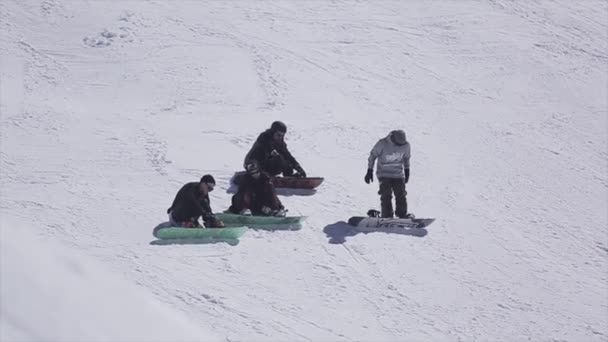 Sochi, Rusko - 2. dubna 2016: Snowboardistů na svahu v lyžařském středisku. Sun. zasněžené hory. Extrémní sport — Stock video