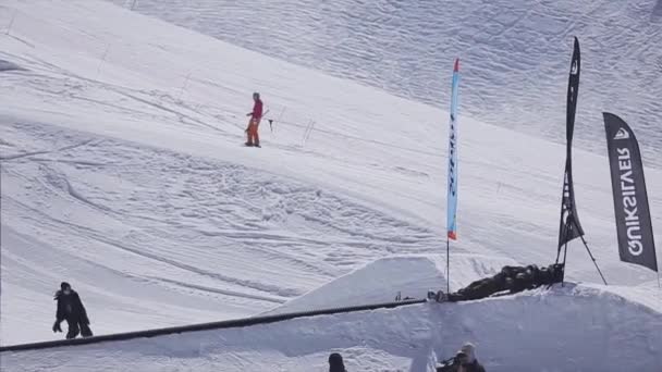 Sochi, Rusko - 2. dubna 2016: Snowboardista, aby upadnout na železnici v lyžařském středisku. Slunečný den. Hory. Lidé. — Stock video