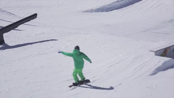 SOCHI, RUSSIA - APRIL 2, 2016: Snowboarder slide on rail on ski resort. Sunny day. Snowy mountains. Extreme — Stock Video