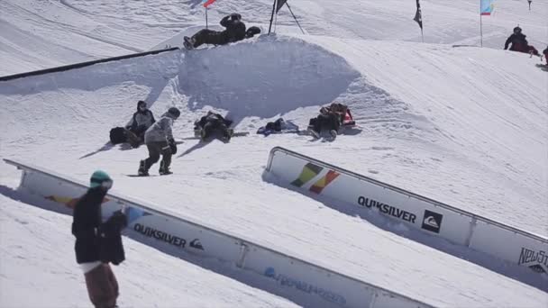 Σότσι, Ρωσία - Σάββατο 2 Απριλίου 2016: Snowboarder διαφάνεια σχετικά με τις σιδηροδρομικές. Κάνει το κόλπο. Χιονοδρομικό κέντρο. Ηλιόλουστη μέρα. Ενεργό αθλητισμό. — Αρχείο Βίντεο