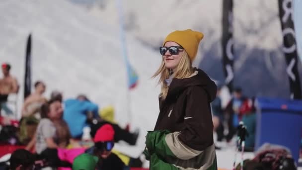 SOCHI, RUSIA - 2 DE ABRIL DE 2016: Niña en gafas de sol relajarse en el campamento. Estación de esquí. Gente. Snowboarders — Vídeos de Stock