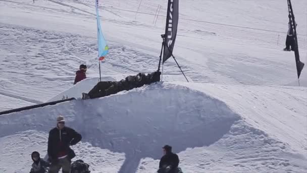 Sochi, Oroszország - április 2-án, 2016: Snowboardos ugrás az ugródeszka, hogy flip a sípálya. Süt a nap. Lovaglás — Stock videók