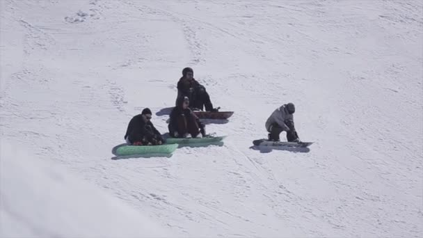 Sochi, Російська Федерація - 2 квітня 2016: Сноубордисти, сидячи на схилі на гірськолижному курорті. Сонячний день. Засніжених гір. Спорт — стокове відео