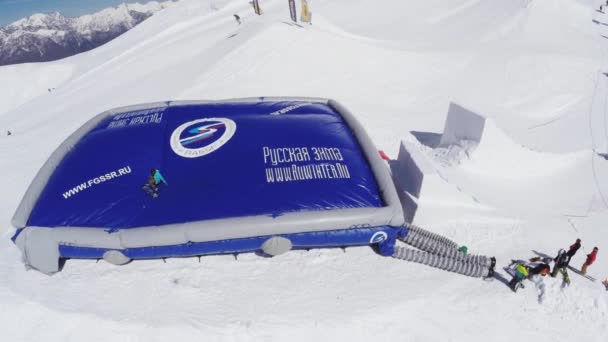 Sochi, Rusland - 2 April 2016: Quadrocopter schieten snowboarder opstaan uit blauwe opleiding trampoline. Zonnige dag — Stockvideo