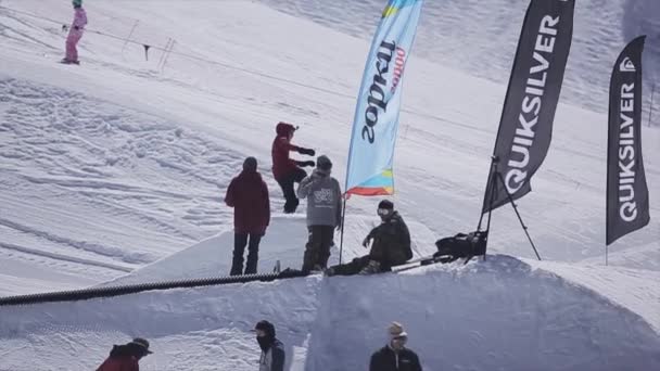 Sochi, Ryssland - April 2, 2016: Snowboardåkare hoppa från springboard på skidorten. Solig dag. Snötäckta berg — Stockvideo