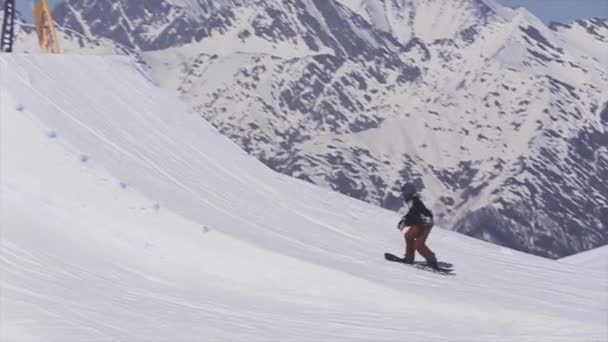 Sochi, Rusko - 2. dubna 2016: Snowboardista skok z odrazový můstek. Lyžařské středisko. Scenérie horské. Aktivní sport — Stock video