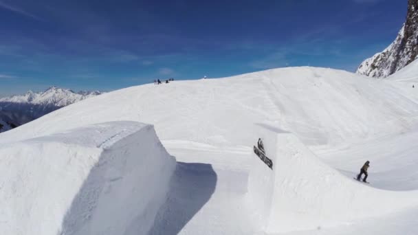 SOCHI, RUSSIA - APRIL 2, 2016: Quadrocopter shoot snowboarder jump from springboard. Mountains. Blue sky. Sport — Stock Video